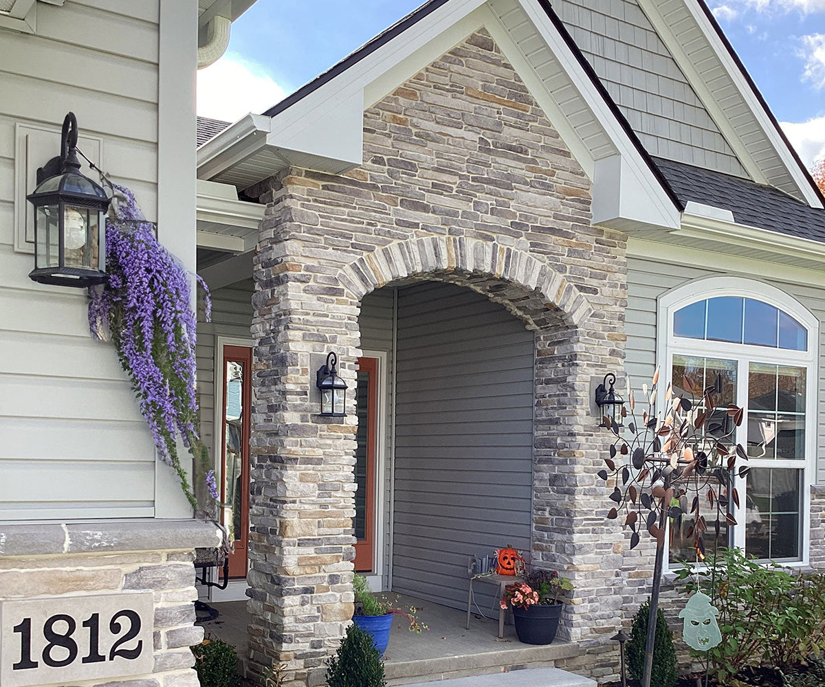 Front of a house with stone archway, decorative elements, and flowers.
