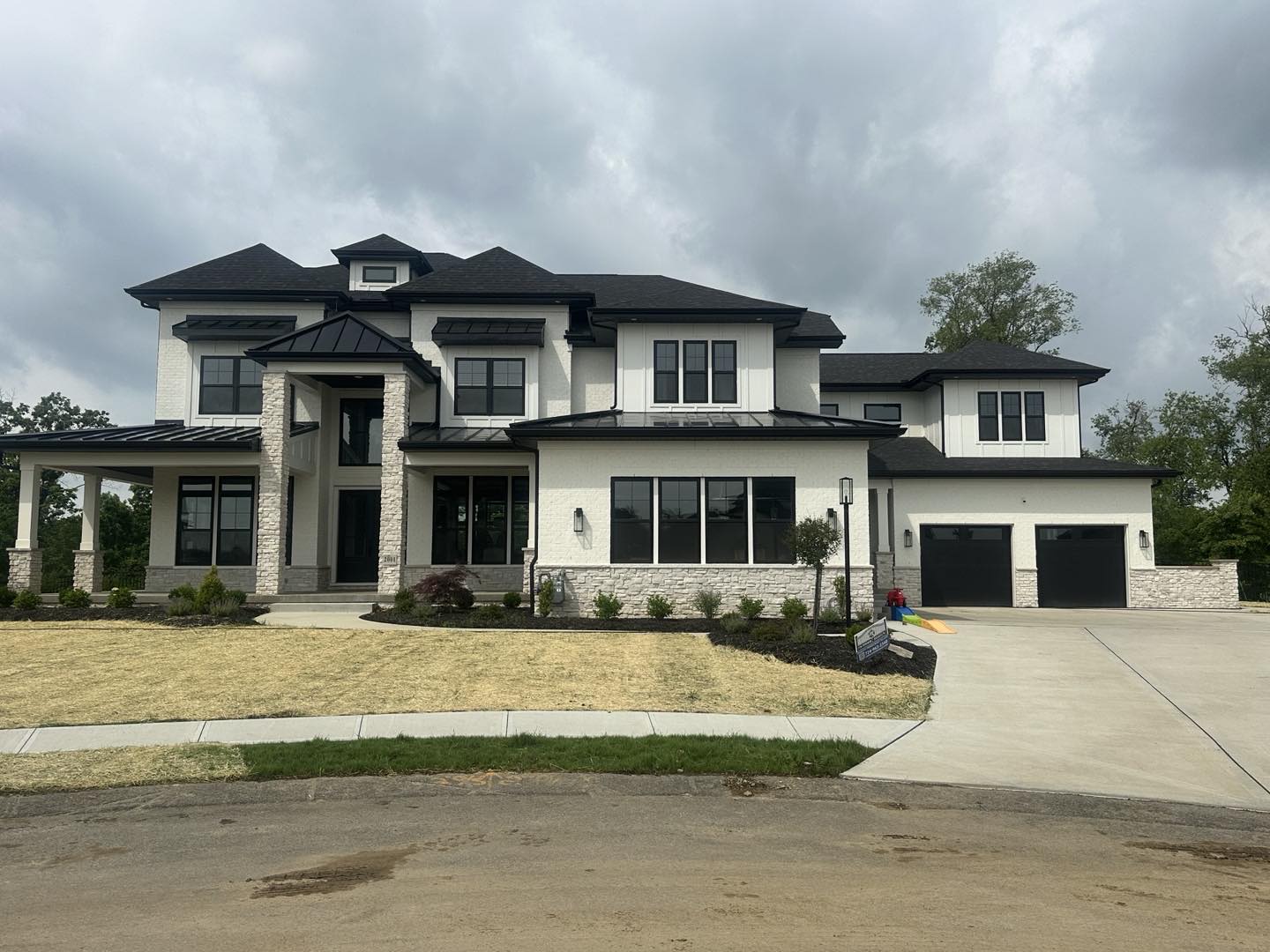 Modern house with white exterior and black roof against a cloudy sky