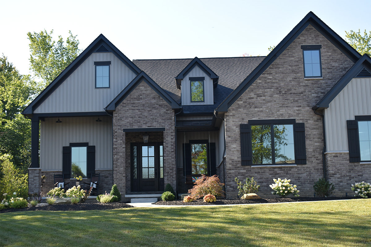 Two-story house with brick and siding exterior, surrounded by greenery.