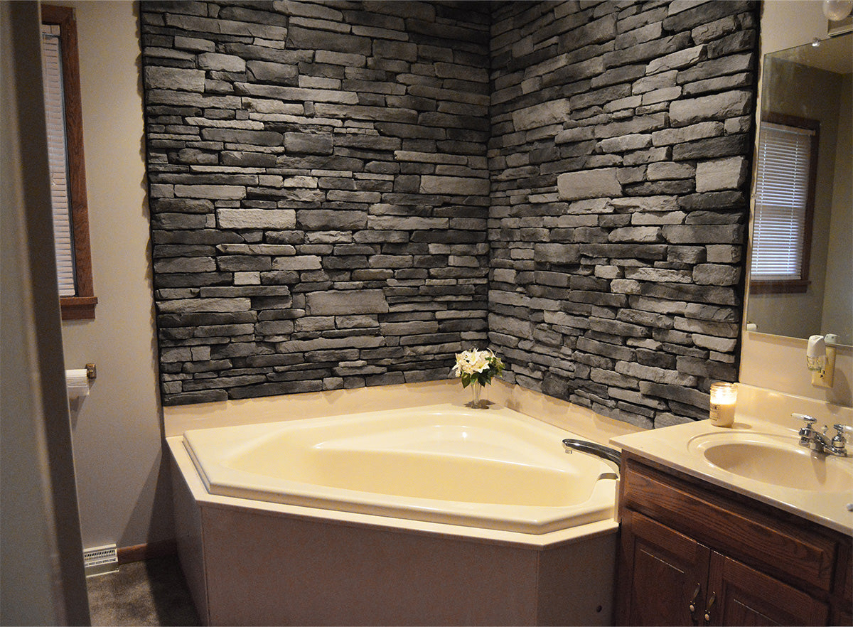 Bathroom with stone wall, corner bathtub, and vanity.