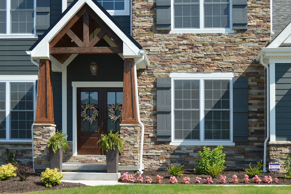 Front entrance of a house with stone facade, wooden door, and decorative elements.