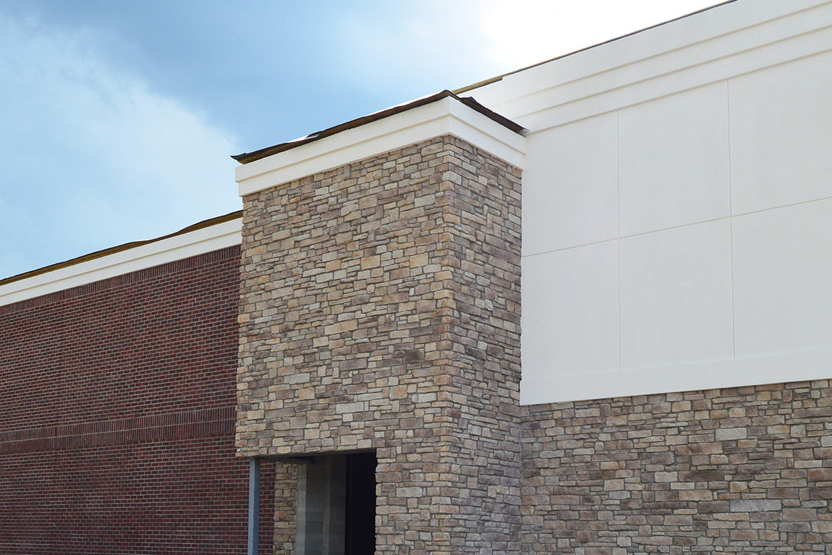Building exterior with stone facade and white trim against a blue sky.