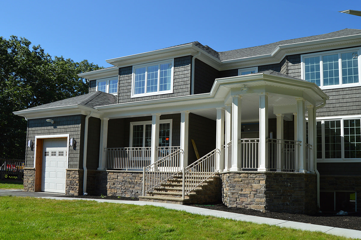 Two-story house with a front porch and stone foundation on a clear day.