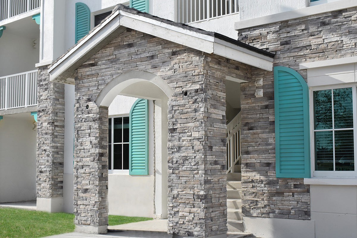 Stone facade of a building with teal shutters and white trim