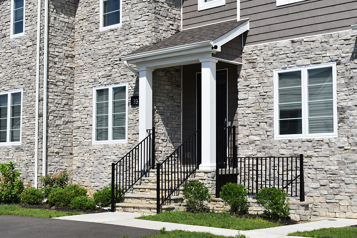 Two-story house with stone facade and black metal staircase