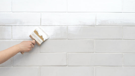 Person applying white grout to a tiled wall