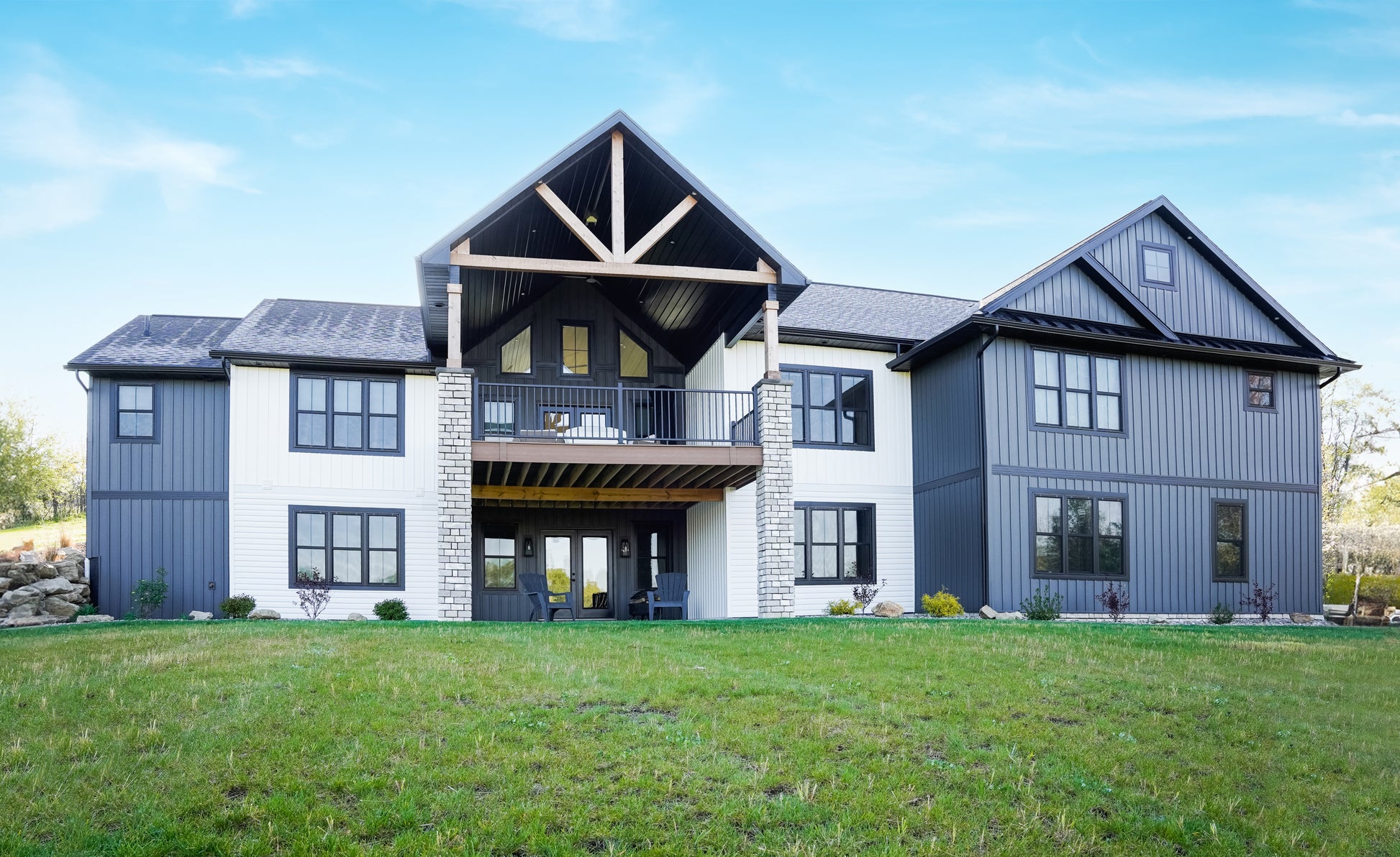 Large modern house with a gray exterior and white accents on a clear day.