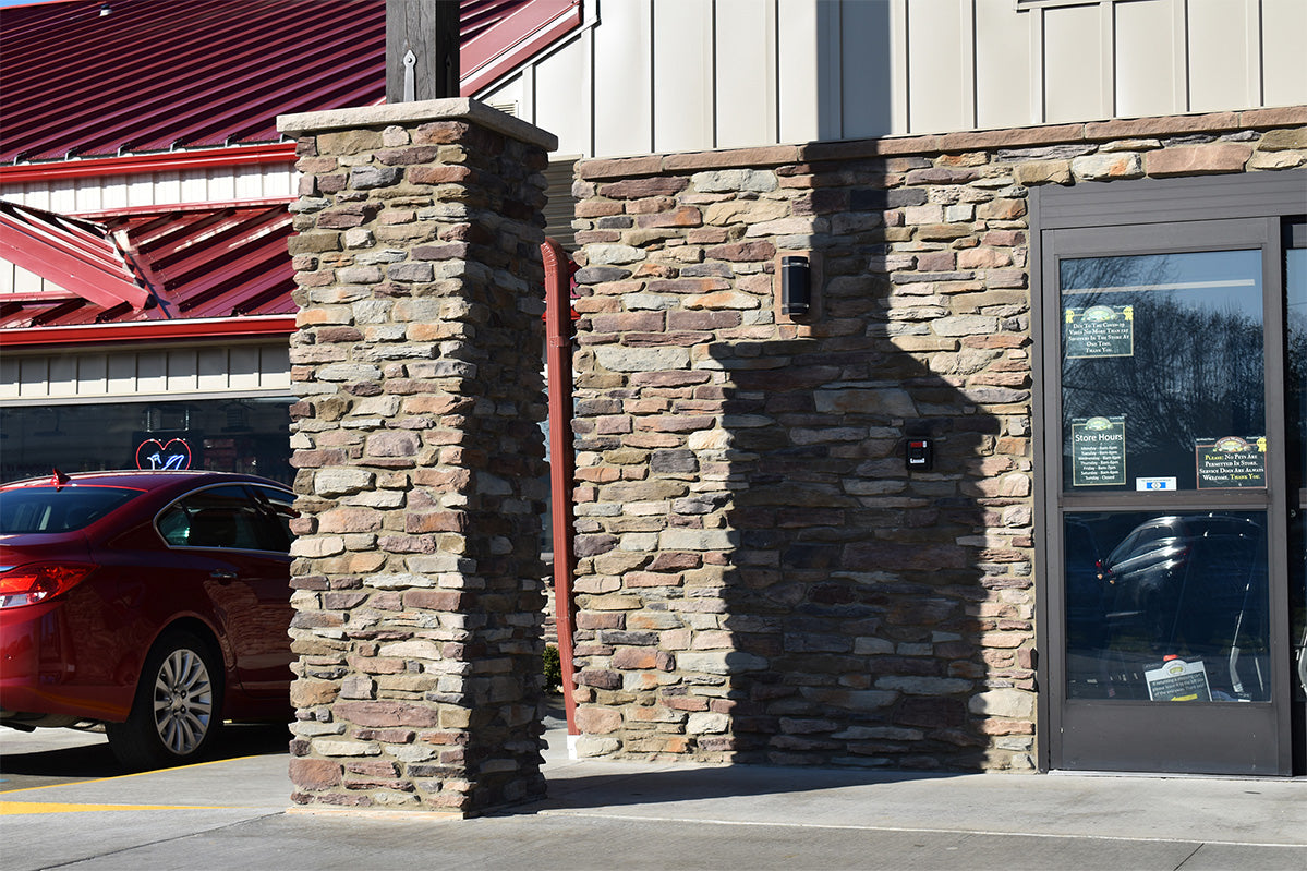 Red car parked outside a building with stone exterior