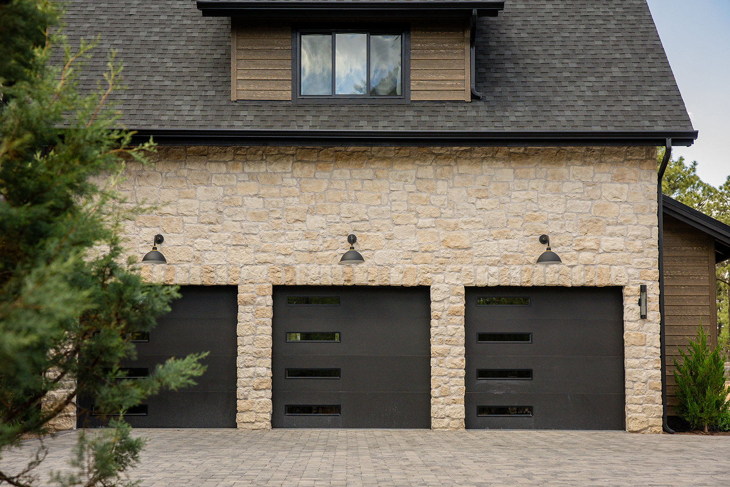 Modern garage with stone facade and black garage doors