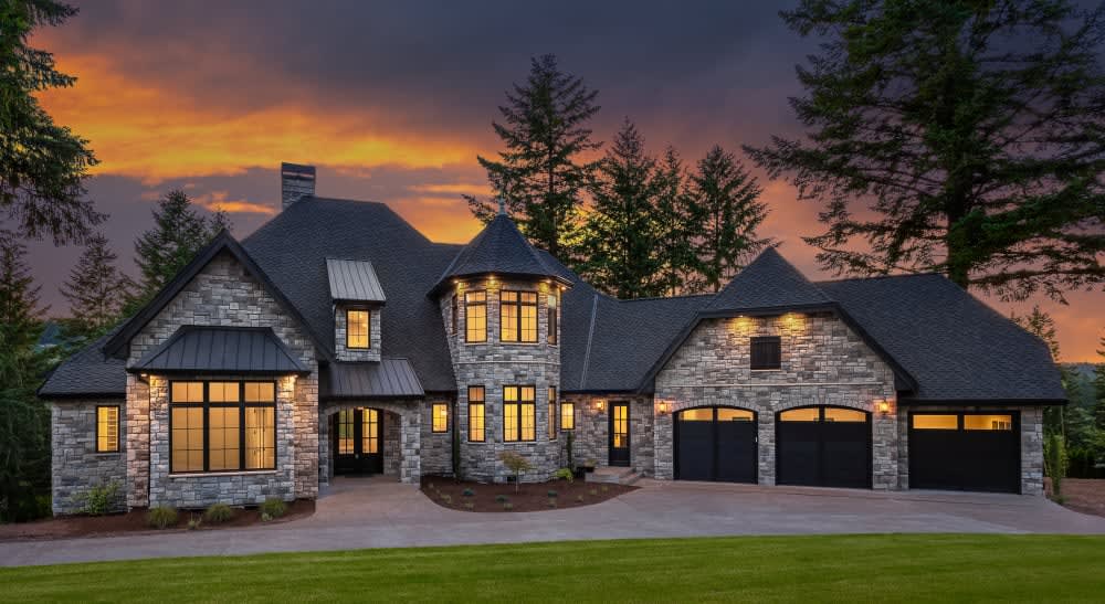 Gray cobblefield stone facade on a gabled home with warm windows at sunset, featuring Cultured Stone Echo Ridge Cobblefield.