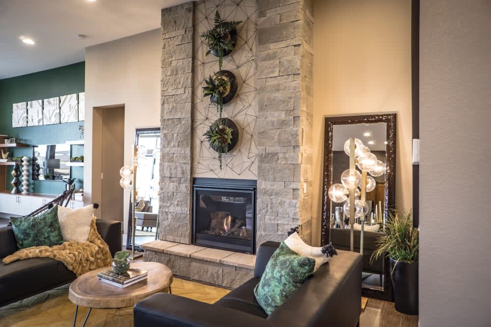 Pale hewn stone fireplace rising above a living room with dark green seating, featuring Cultured Stone Span Hewn Stone.