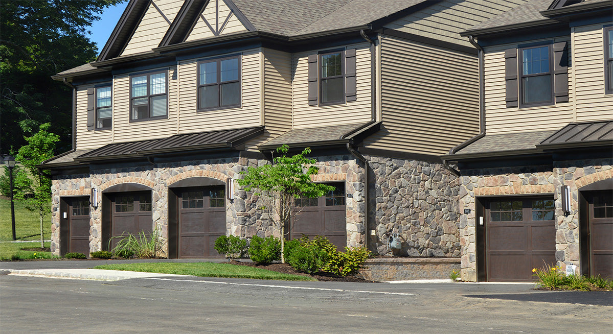 Two-story residential building with stone facade and multiple garage doors.