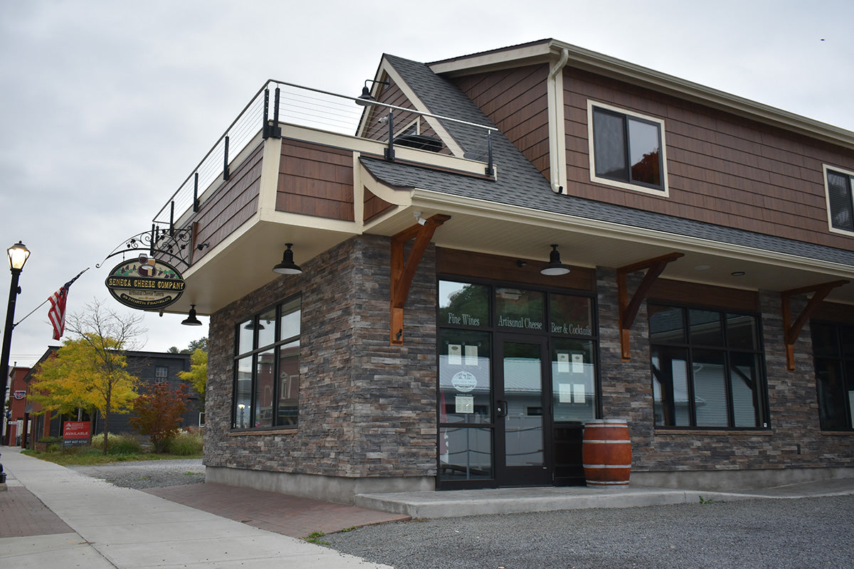 Two-story building with a mix of stone and wood exterior, featuring large windows and a sign.