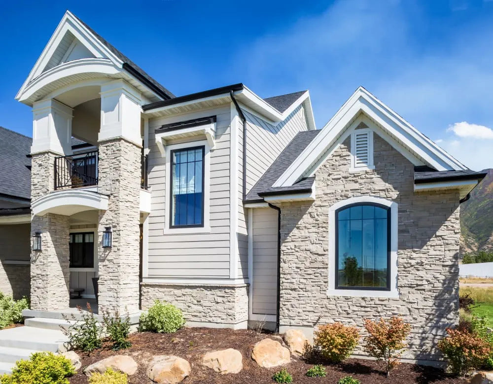 Light dry-stack stone around arched windows and the entrance of a gabled home, featuring Dutch Quality Arizona Dry Stack.