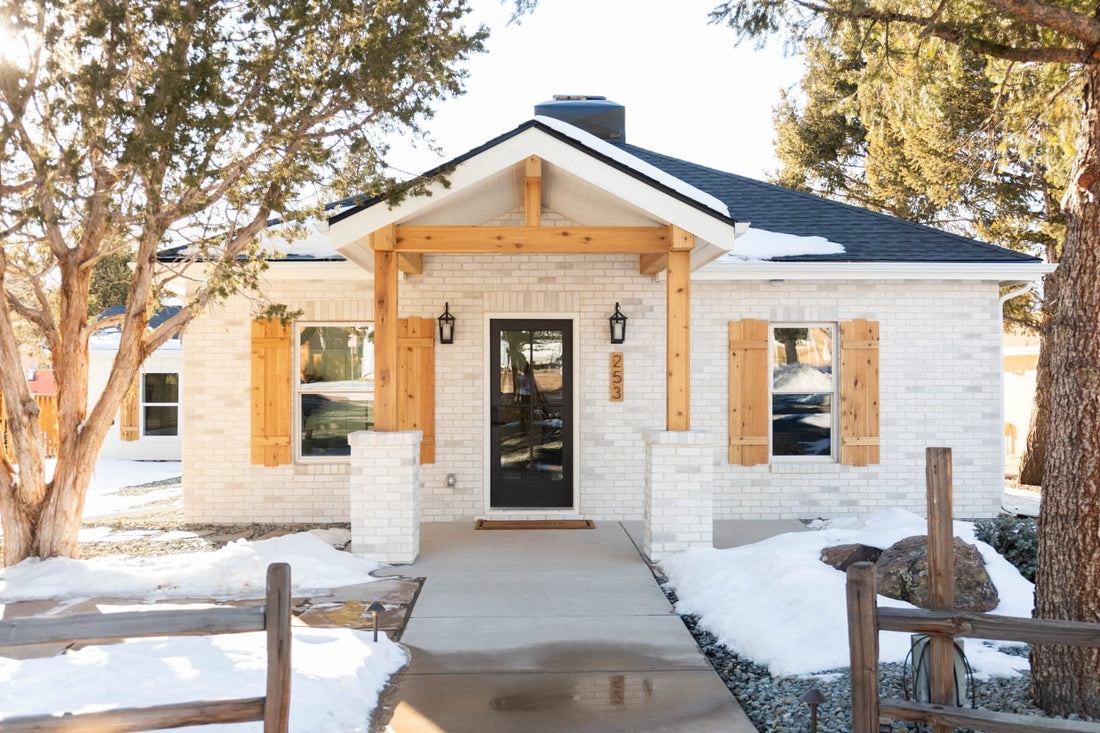 White thin brick on a small home with wood porch posts and a black front door, featuring Eldorado Chalk Dust TundraBrick.