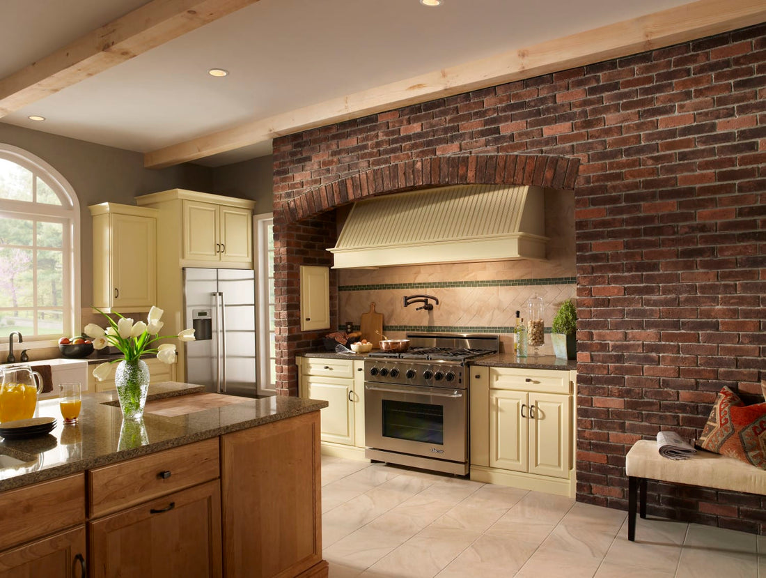 Warm dark thin brick around a kitchen range with pale cabinets and a broad metal hood, featuring Eldorado Hartford TundraBrick.