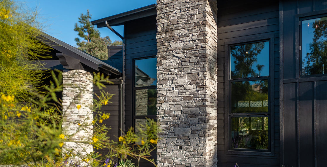 Gray ledgestone columns beside tall black-framed windows and dark siding, featuring Creative Mines® Fogbank Craft Peak Ledge.
