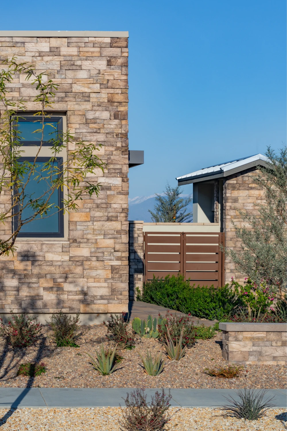 Warm gray modular stone on a contemporary facade beside tall black-framed windows, featuring Creative Mines® Greypearl Craft Split Modular in a 50/50 blend of 2.5-inch and 5-inch profiles.