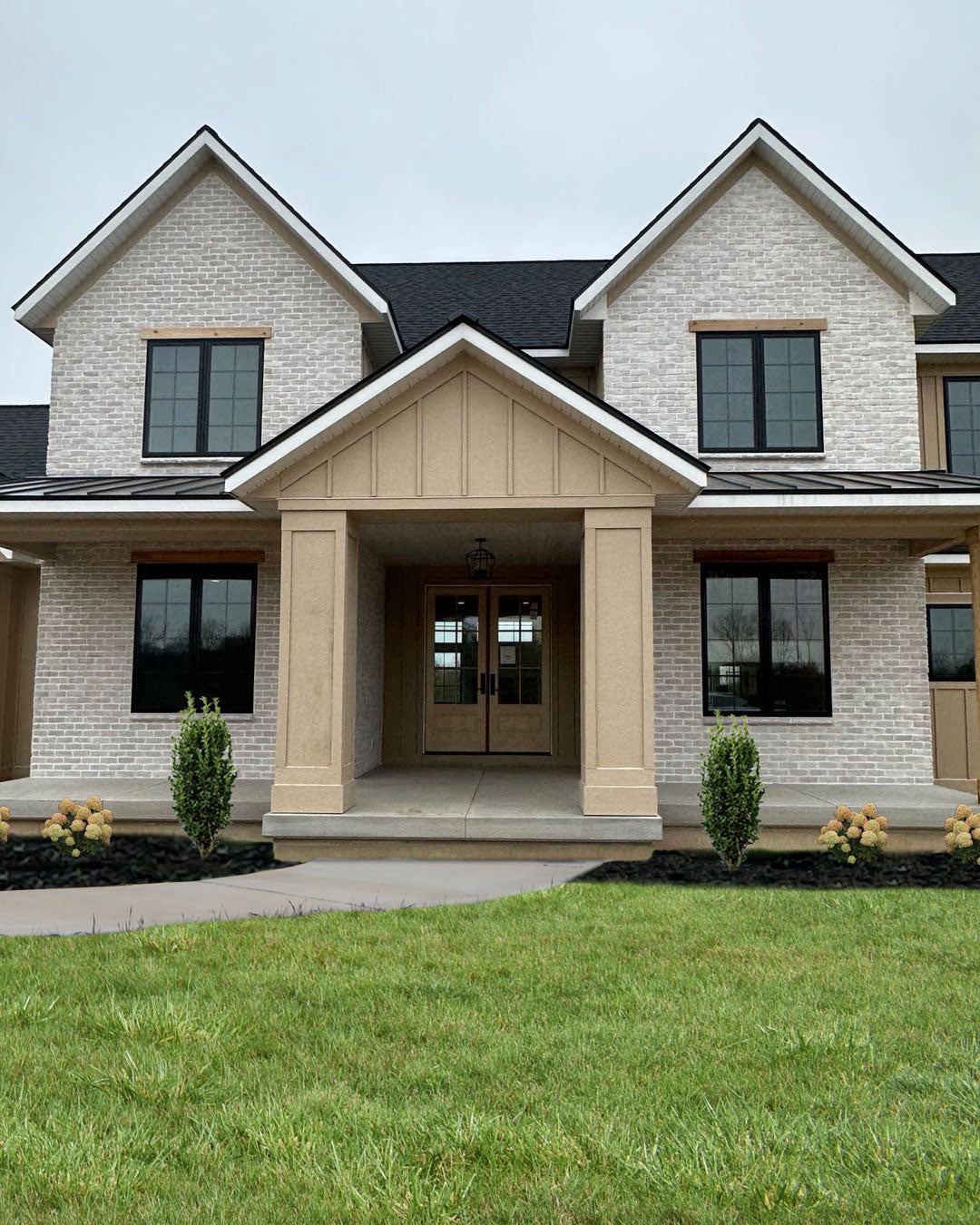 Light thin brick on a two-story home with black-framed windows and a recessed entry, featuring Prestige White Onyx Thin Veneer Brick.