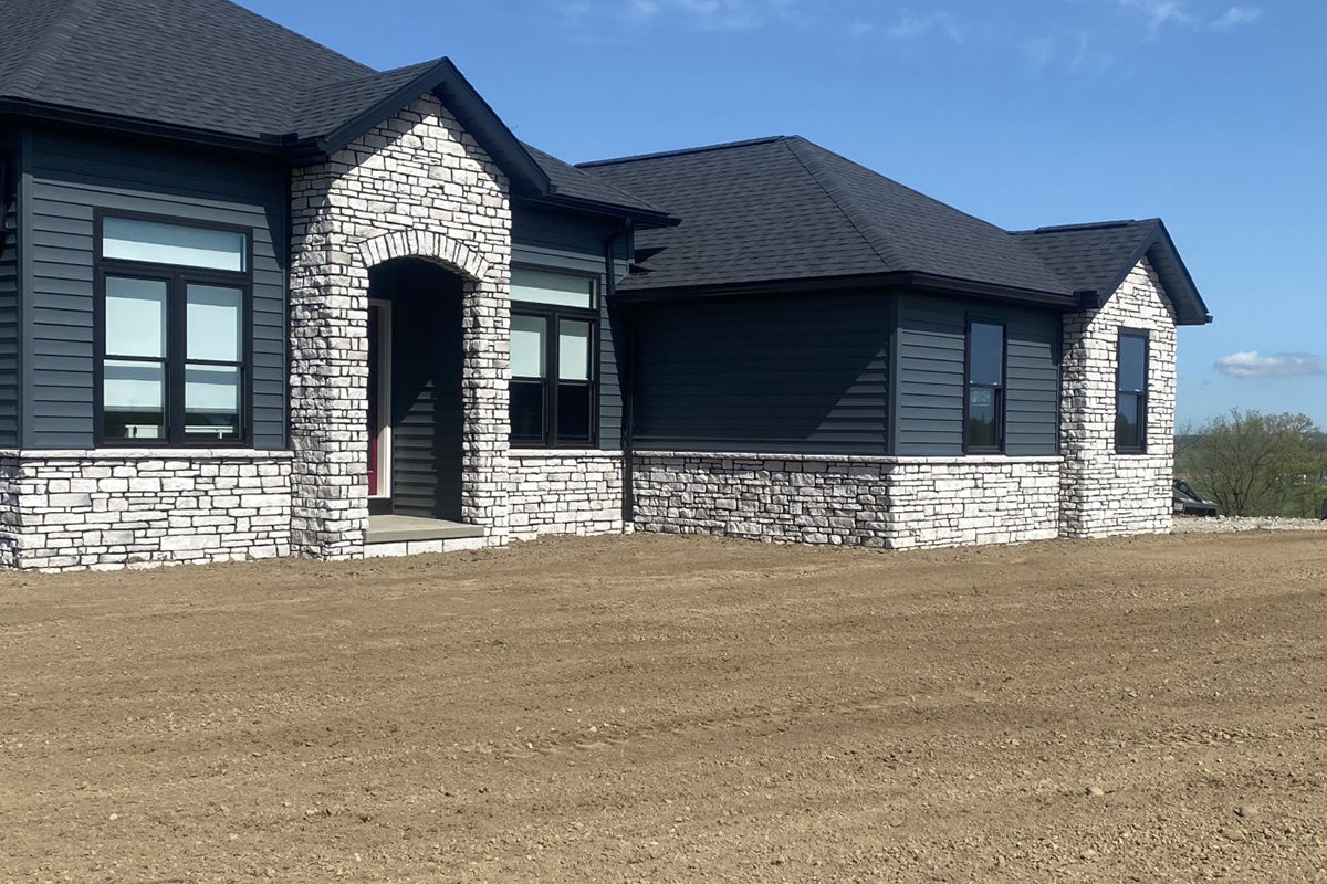Modern house with gray siding and stone accents on a clear day.