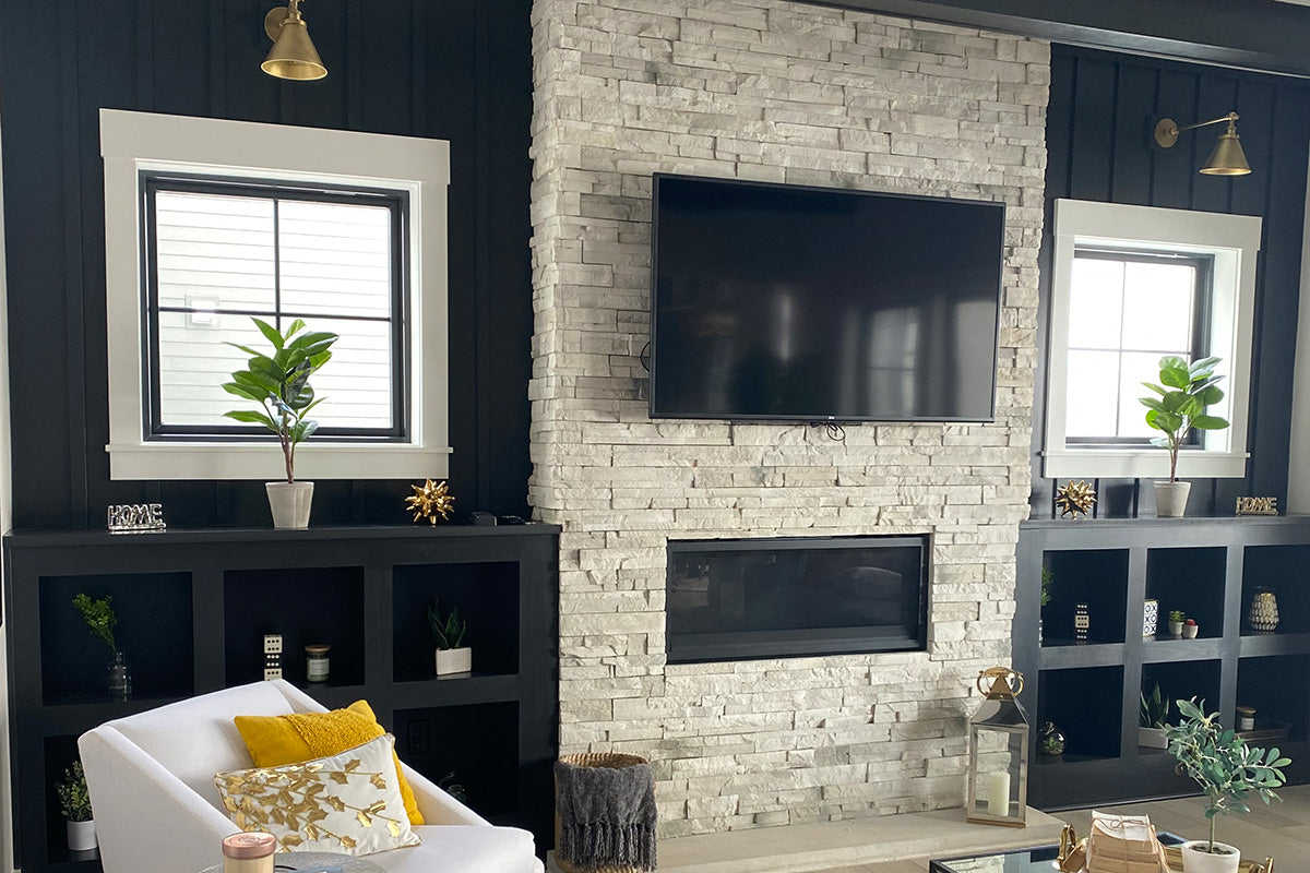 Living room with stone fireplace, television, and bookshelves.