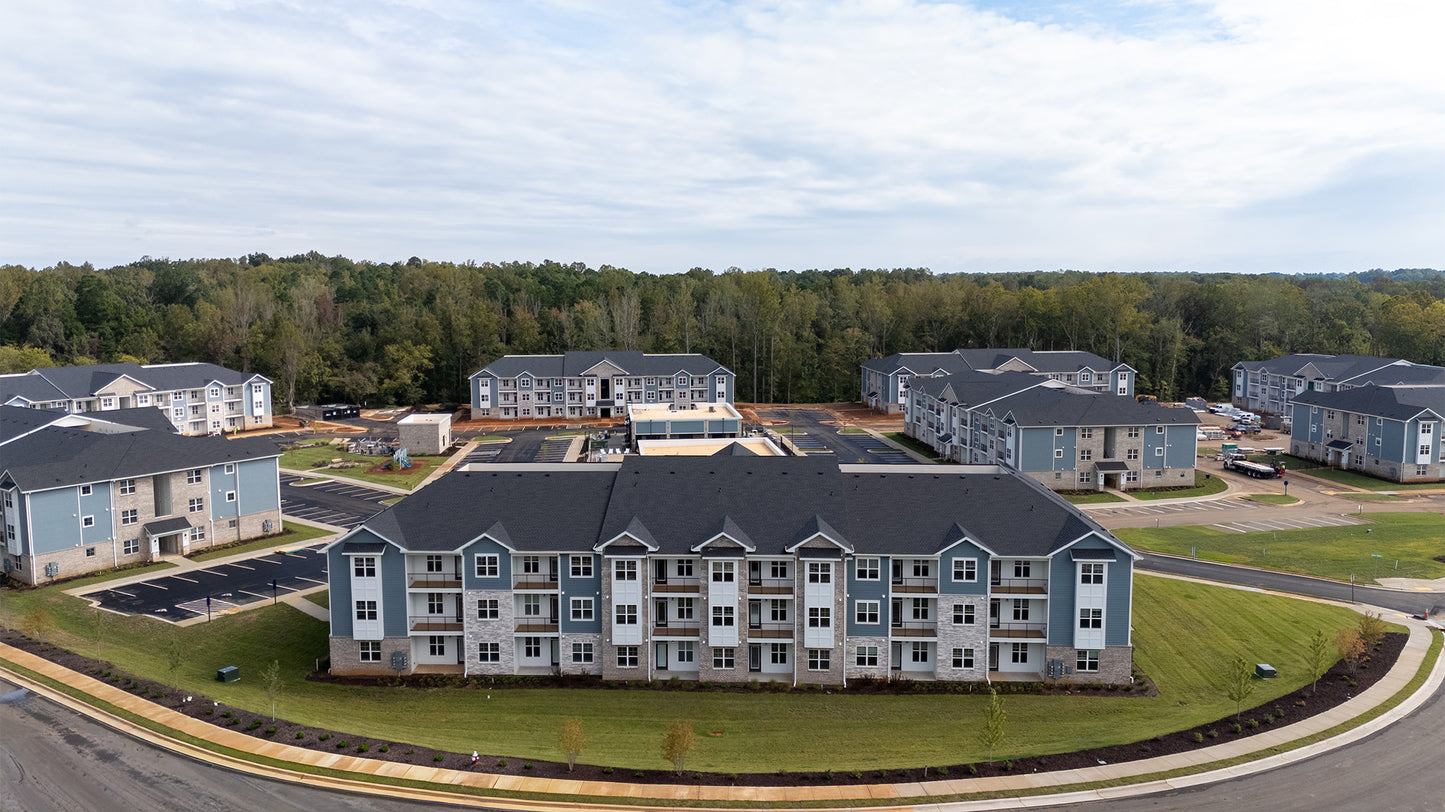 Aerial view of a residential complex with multiple buildings surrounded by trees.