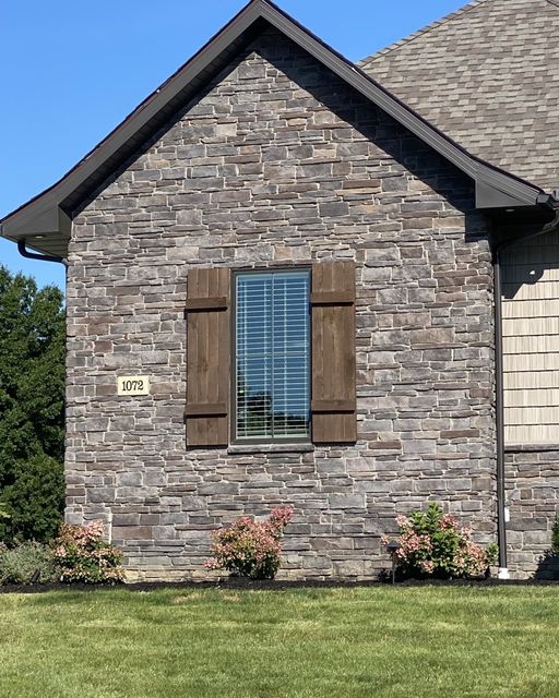 Stone house exterior with a window and address plaque on a clear day