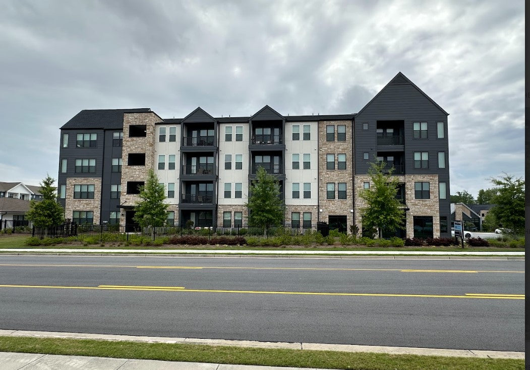 Multistory apartment building with black and beige facade on a cloudy day.