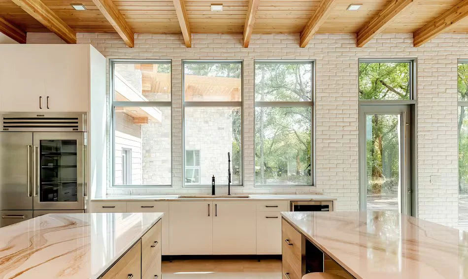 Modern kitchen with white brick walls, wooden beams, and large windows.