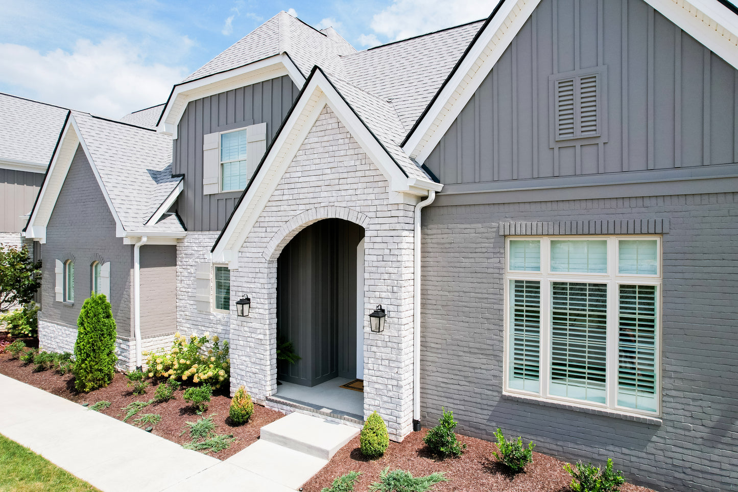 Two houses with gray and white exteriors, featuring a well-maintained garden.