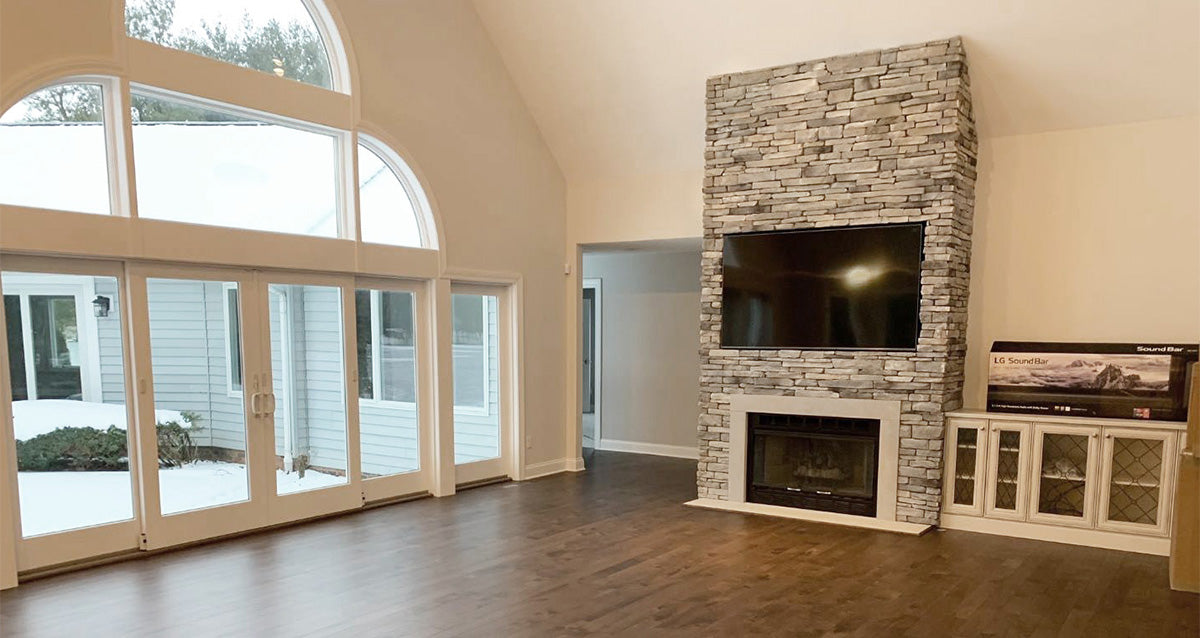Living room with stone fireplace, TV, and large windows