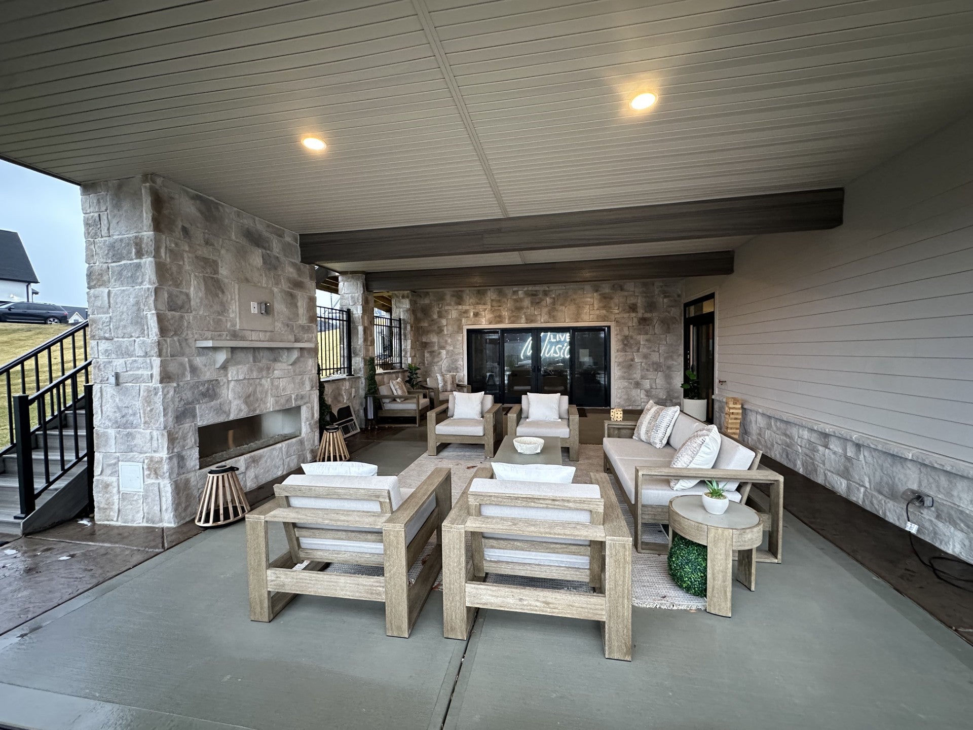 Outdoor patio area with wooden furniture and a stone fireplace.