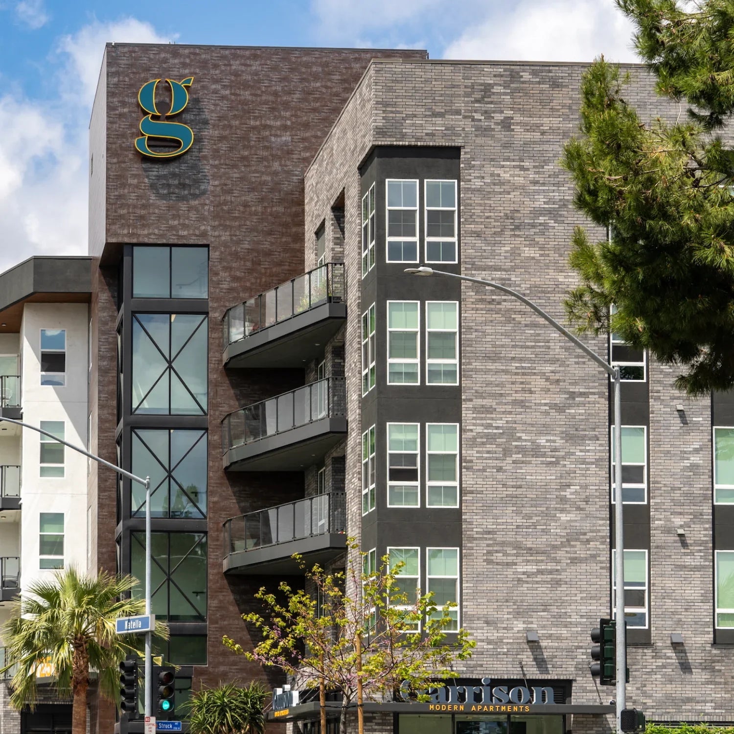 Modern apartment building with balconies and a prominent logo on a clear day.