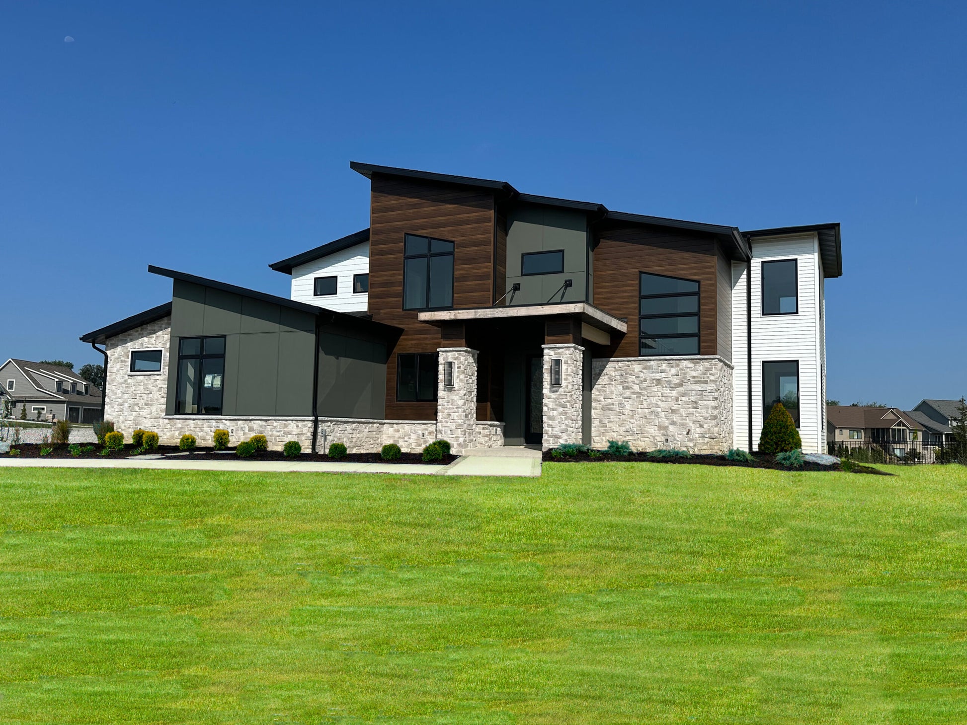 Modern house with wooden and stone exterior against a clear blue sky