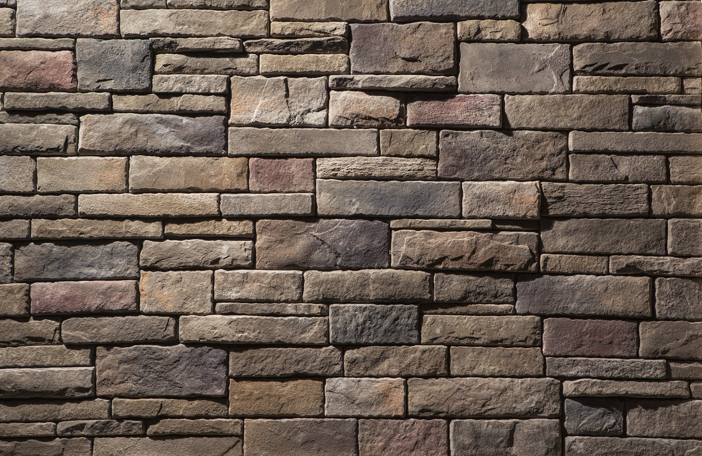 Pattern of stacked stone bricks in various shades of brown and gray.