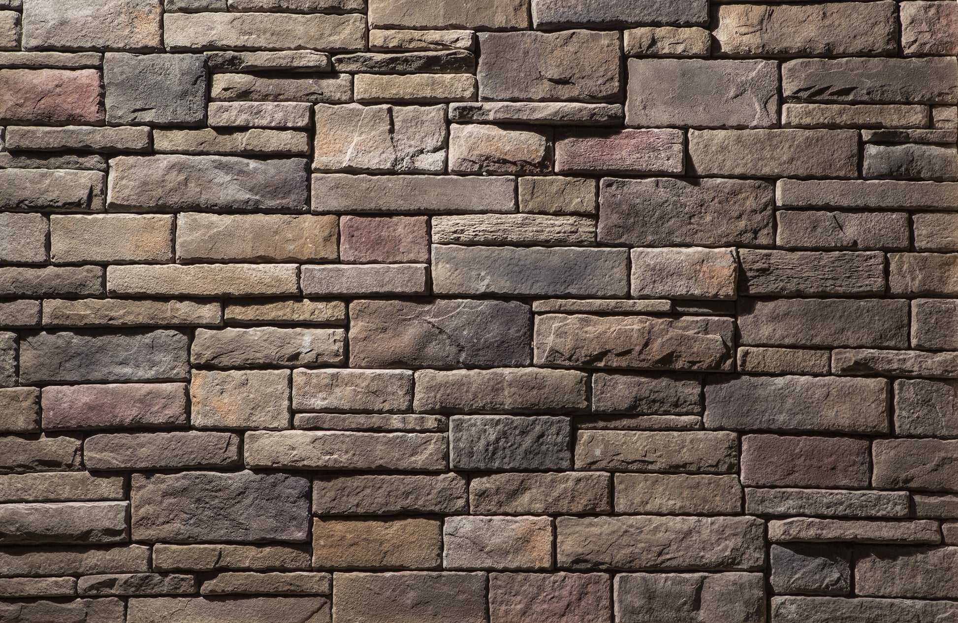 Pattern of stacked stone bricks in various shades of brown and gray.