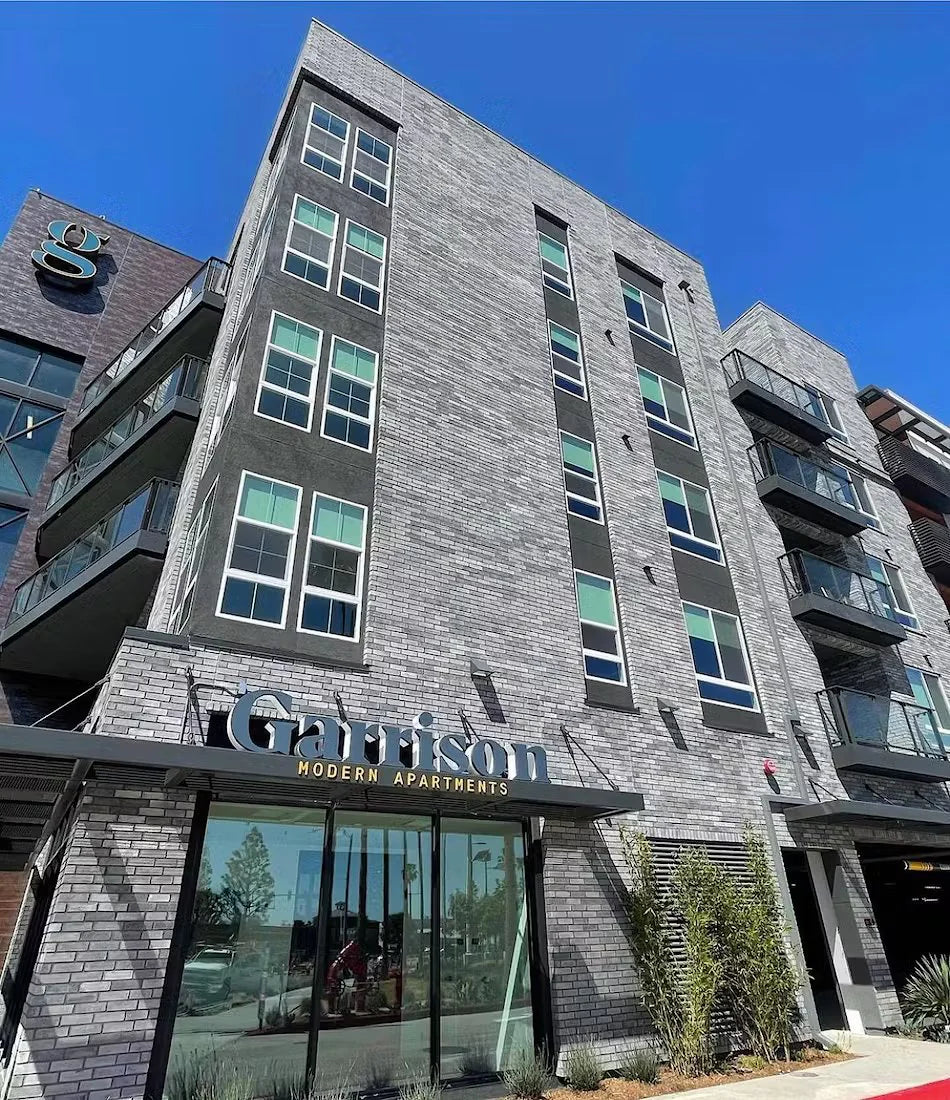 Modern apartment building with 'Garrison' branding against a clear blue sky.