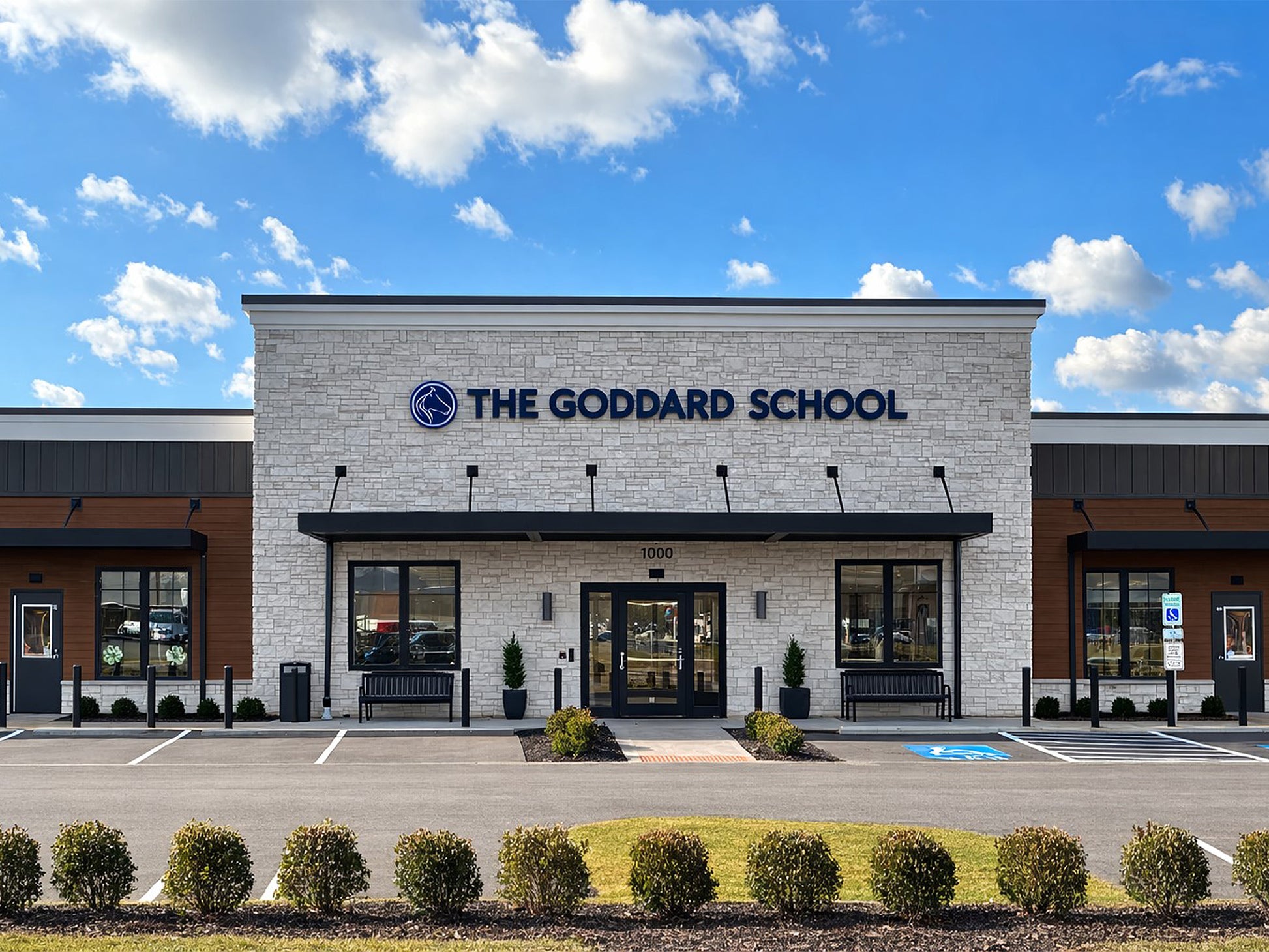 The Goddard School building with a clear blue sky and clouds.