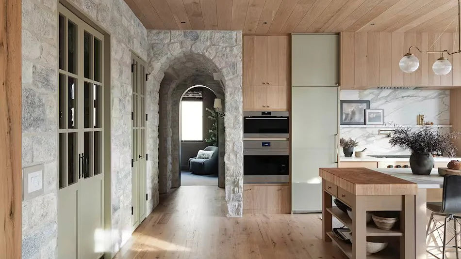 Modern kitchen with wooden cabinets, stone walls, and a dining area.