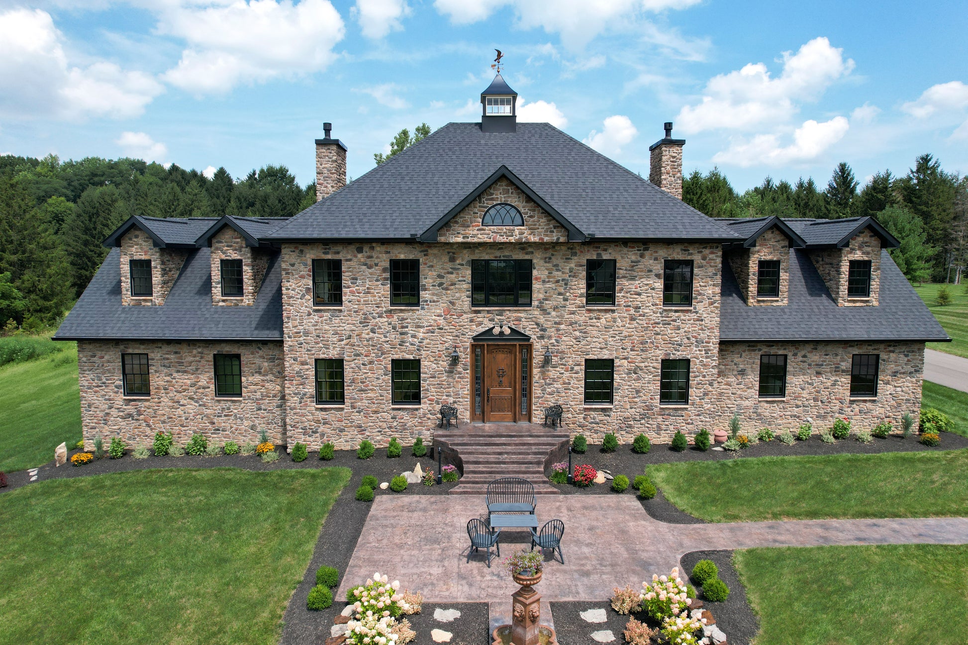 Large stone mansion with a well-manicured lawn and garden