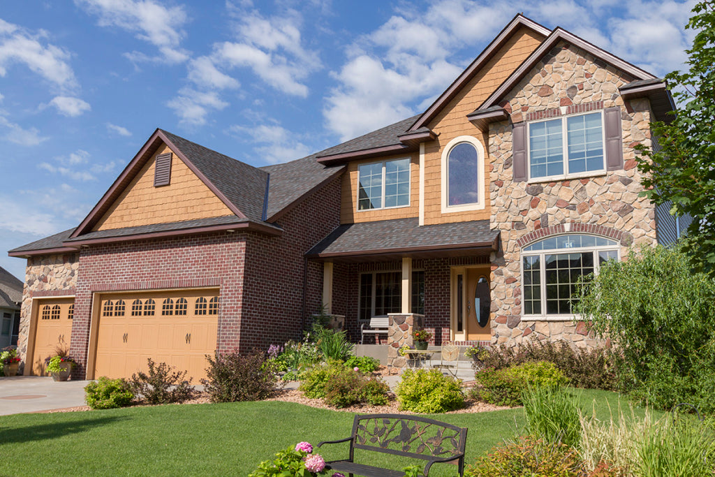 Brown and gold splitface stone across a two-story home's gables and front porch, featuring Boulder Creek Stone Buckeye Blend Splitface.