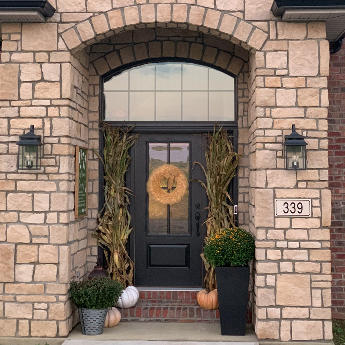 Front door of a house with decorative wreath and pumpkins, stone facade, and address number 339.