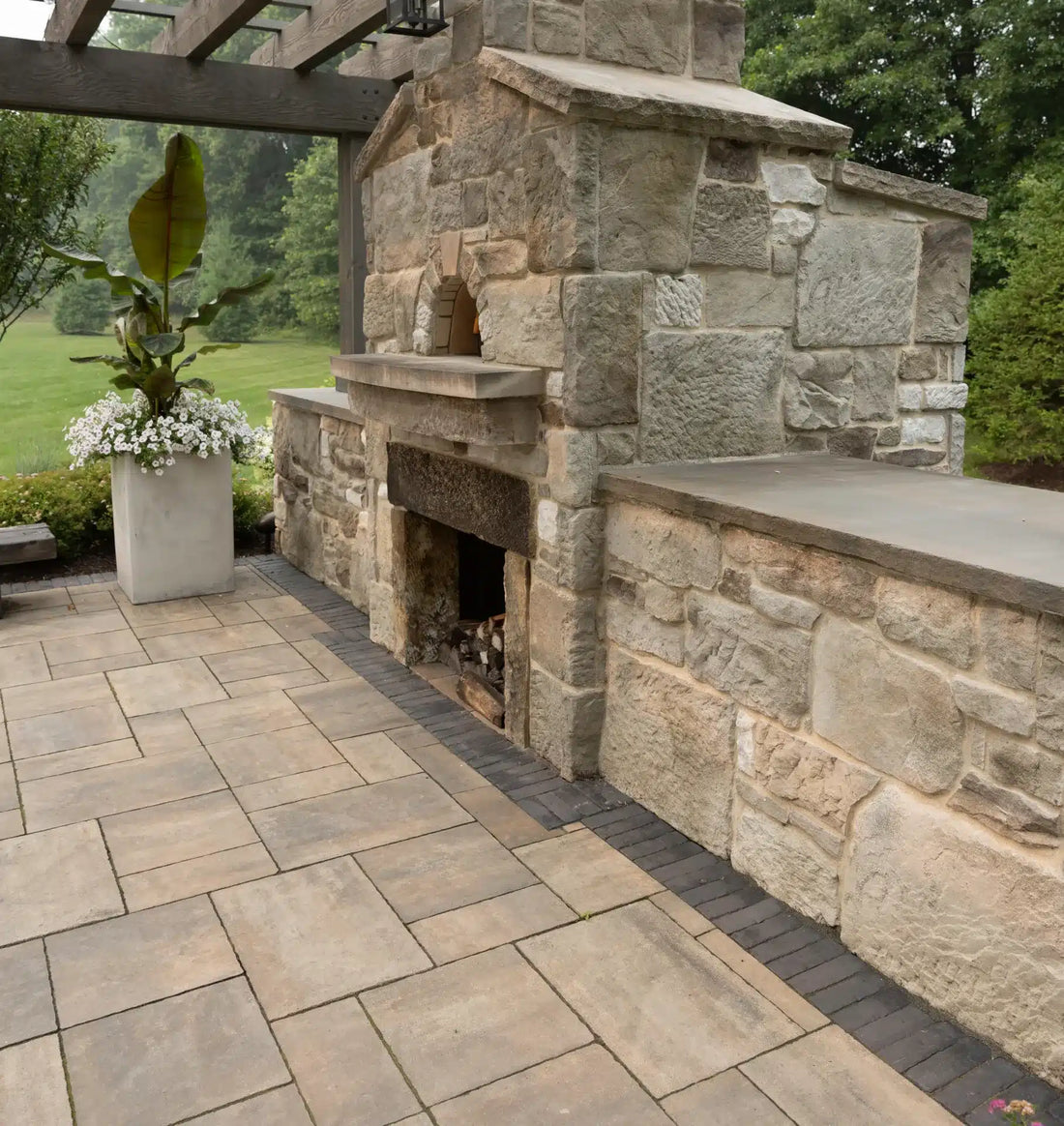 Rustic stone outdoor fireplace with flanking counter-height stone walls, featuring Casa Di Sassi Bella Old World.