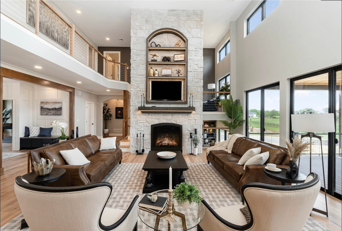 Casa Di Sassi Niveo Volterra light stone fireplace in a double-height living room with wood and leather accents.