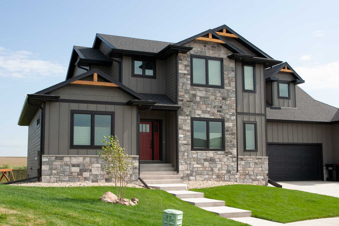 Gray volterra stone around a modern home's red door, windows and timber gables, featuring Casa Di Sassi Turin Volterra.