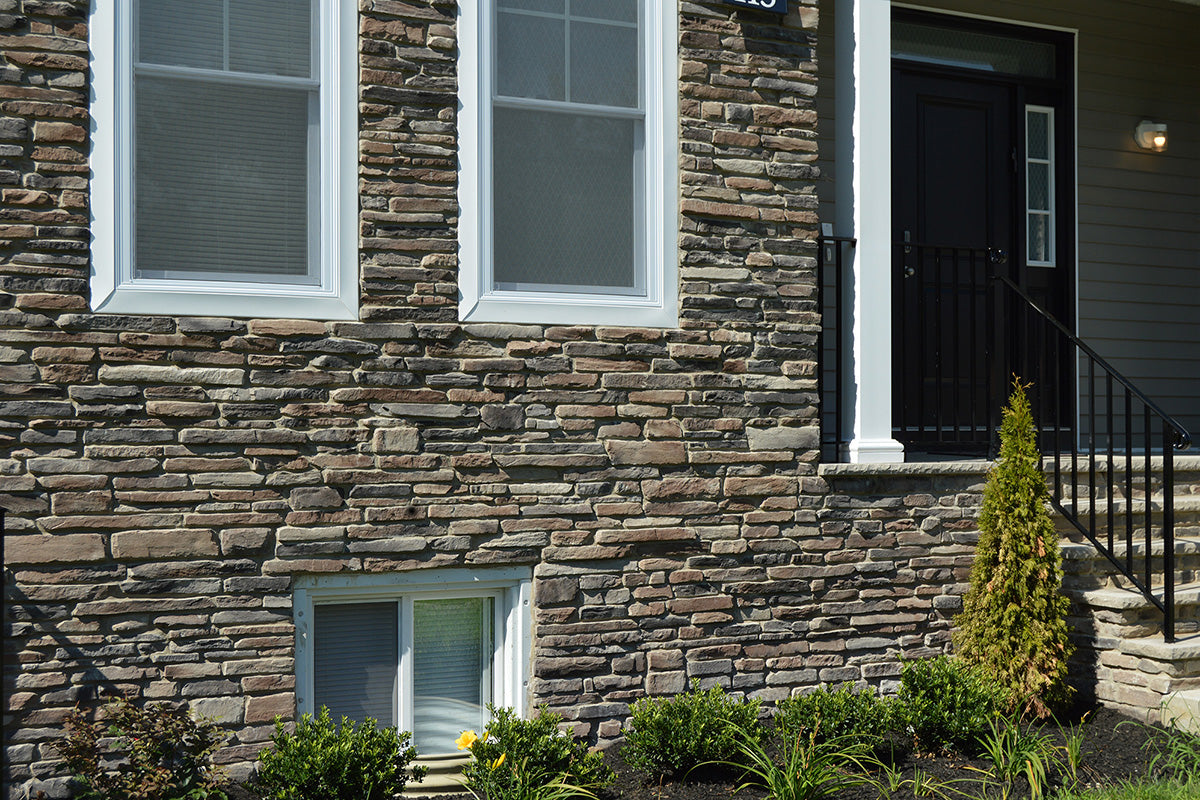 Stucco exterior of a house with stone-like texture, windows, and a door.