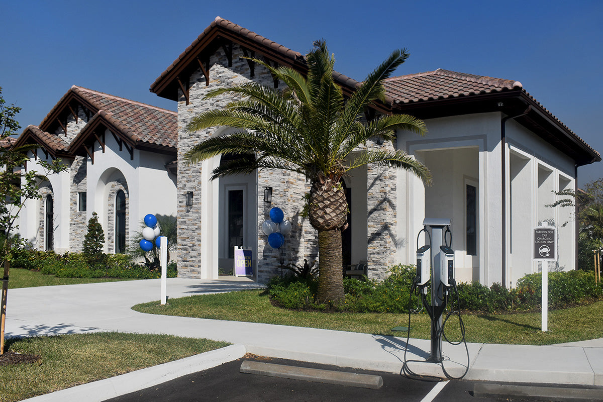 Modern house with stone facade and palm tree in front, featuring a charging station.