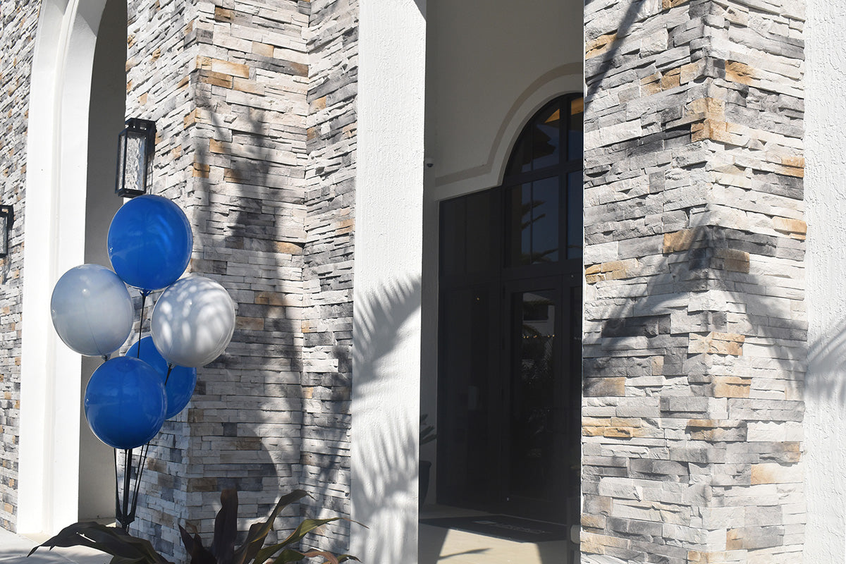 Blue and white balloons on a stand against a stone wall.