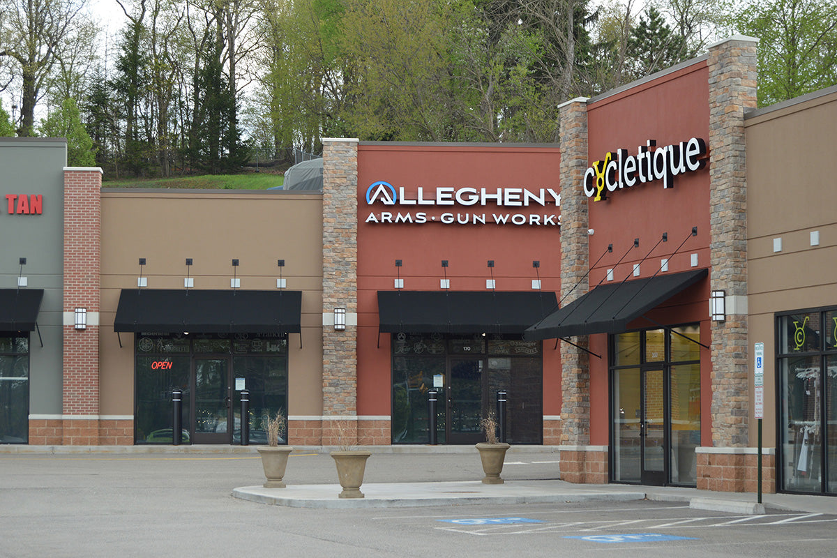 Commercial building with 'Allegheny Arms-Gun Works' and 'Cycletique' signs.