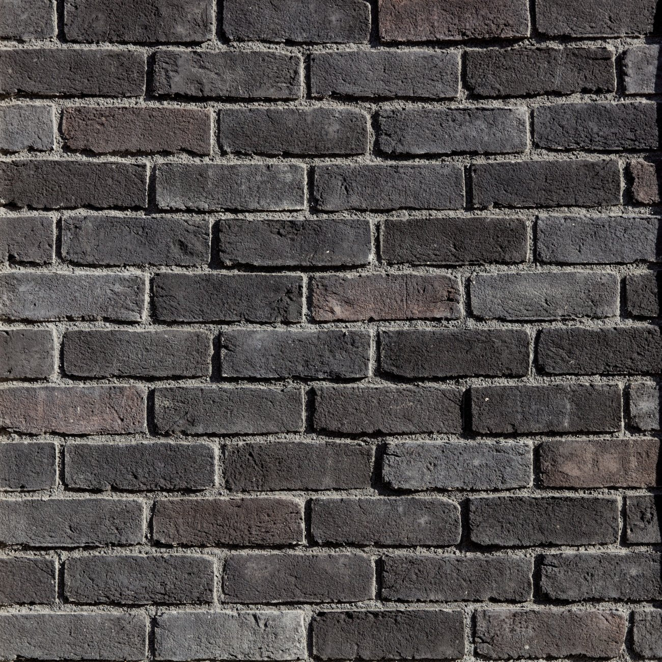 Eldorado Ironside TundraBrick thin brick-style stone veneer in deep gray, charcoal, and brown tones with textured surface